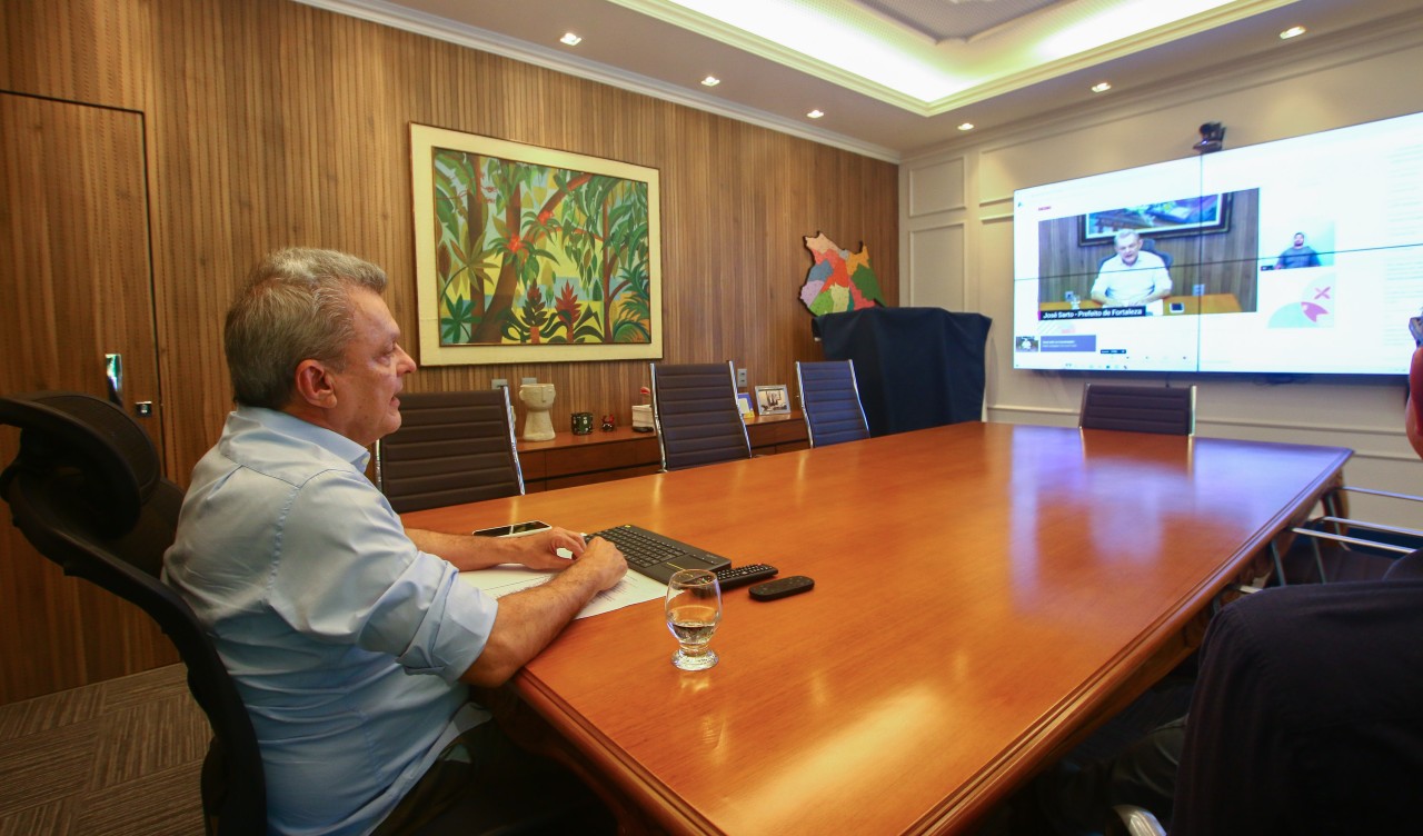 sarto numa mesa de reunião diante de um telão